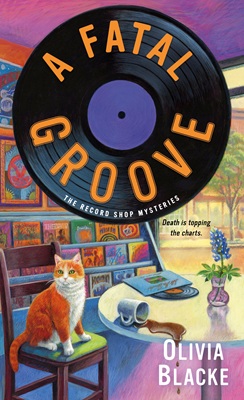 Book cover features a vinyl record printed with the title "A Fatal Groove, The Record Shop Mysteries." The cover image includes around table with spilled coffee cup and a record partly out of its sleeve, plus a blue flower in a vase. A cat sits on a chair at the table. The background is a rack of record albums.
